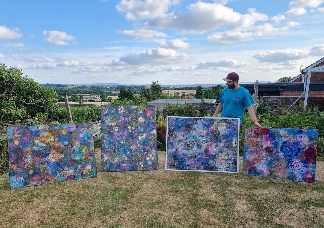 Joe in his garden with four of his paintings