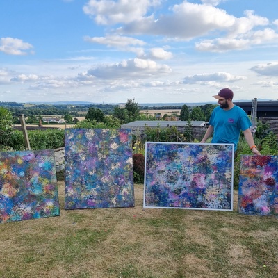 Joe in his garden with four of his paintings