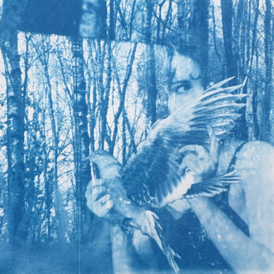 Anne Guest - woman looking from behind a bird wing