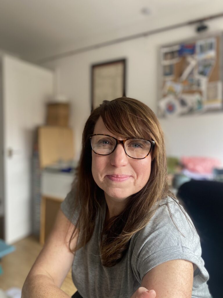 Photo of Katie in her office space with mood-boards and inspiration on the wall.