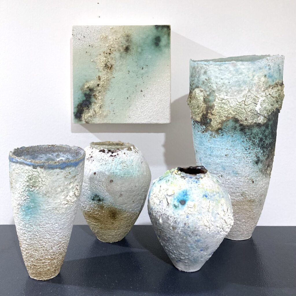 A group of four ceramic vessels and a ceramic wall panel.